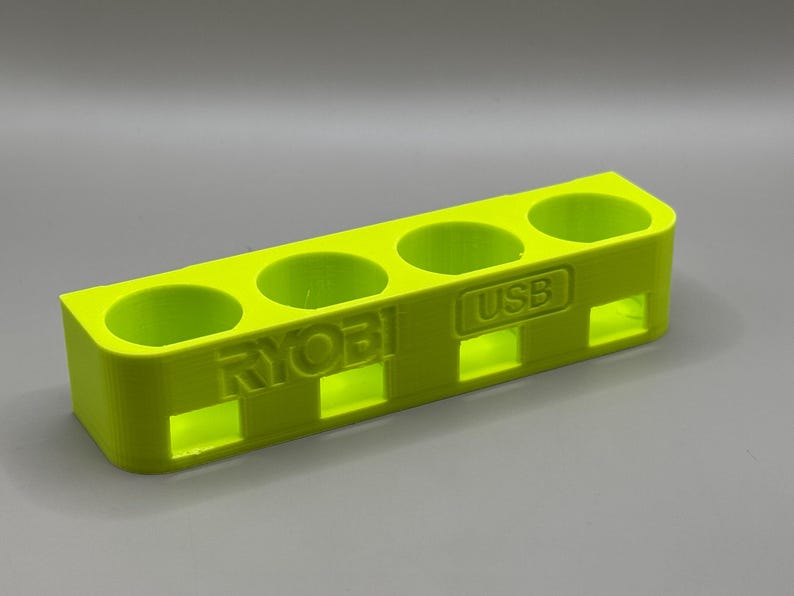 K&ouml;nnte beinhalten: Ein leuchtend gelber Plastik-Organizer mit f&uuml;nf F&auml;chern zum Aufbewahren von Batterien. Der Organizer tr&auml;gt die Aufschrift "RYOBI" und "USB".