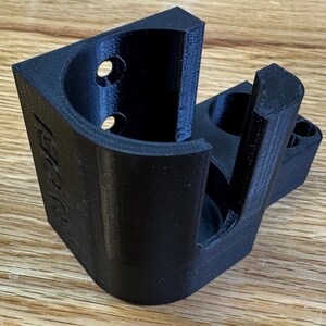Peut inclure: Un support mural imprim&eacute; en 3D noir avec une ouverture circulaire pour maintenir un objet cylindrique. Le support a une petite ouverture rectangulaire sur le c&ocirc;t&eacute;.
