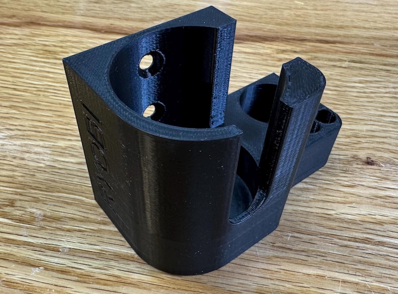 Peut inclure: Un support mural imprim&eacute; en 3D noir avec une ouverture circulaire pour maintenir un objet cylindrique. Le support a une petite ouverture rectangulaire sur le c&ocirc;t&eacute;.