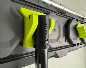 Könnte beinhalten: Nahaufnahme eines schwarzen Metallpfostens mit einem daran befestigten grünen Plastikhaken. Der Haken ist mit "Better Grip Products" beschriftet.