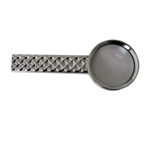 Pode incluir: Uma lupa de prata com um design de nó celta na alça.