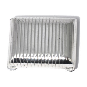 Puede incluir: Una caja rectangular de plata con un diseño acanalado.