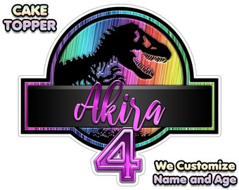 May include: A rainbow-coloured Jurassic Park logo cake topper with a dinosaur silhouette, the name "Akira" and the number "4" in pink and purple. The text "We Customize Name and Age" is also included.