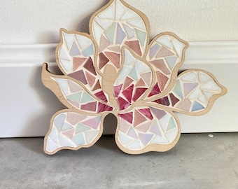 Könnte beinhalten: Eine Wandkunst aus Holzmosaik mit einer Blume, die mit rosa, weißen und hellblauen Glasfliesen verziert ist. Die Blume ist in einem stilisierten Design mit einer zentralen Blüte und Blütenblättern.