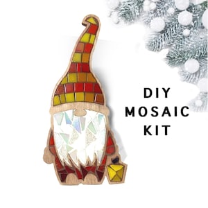 Puede incluir: Kit de mosaico de gnomo de madera con un sombrero y barba de mosaico coloridos. El sombrero presenta azulejos rojos, amarillos y naranjas. La barba est&aacute; hecha de piezas de mosaico iridiscentes. El gnomo sostiene una linterna amarilla. El texto en la imagen dice "DIY MOSAIC KIT."