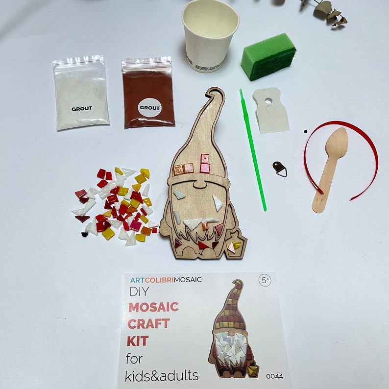 Puede incluir: Un kit de manualidades de mosaico para ni&ntilde;os y adultos, con una figura de gnomo de madera y azulejos de vidrio de colores. Incluye lechada, una esponja, una taza y una cuchara de madera. El embalaje muestra un mosaico de gnomo terminado.