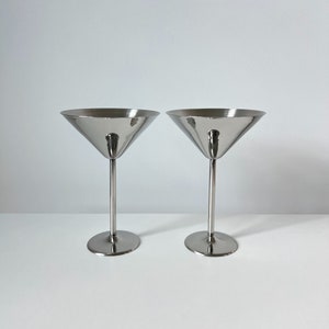 Impress your guests with these vintage Beckmann and Rommerskirchen stainless steel cocktail dessert ice cream cups. Made in 80s Germany, their sleek design and tall silver stems bring timeless charm to your table. Serve drinks or desserts in style.