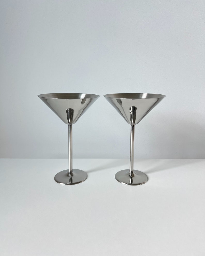 Impress your guests with these vintage Beckmann and Rommerskirchen stainless steel cocktail dessert ice cream cups. Made in 80s Germany, their sleek design and tall silver stems bring timeless charm to your table. Serve drinks or desserts in style.