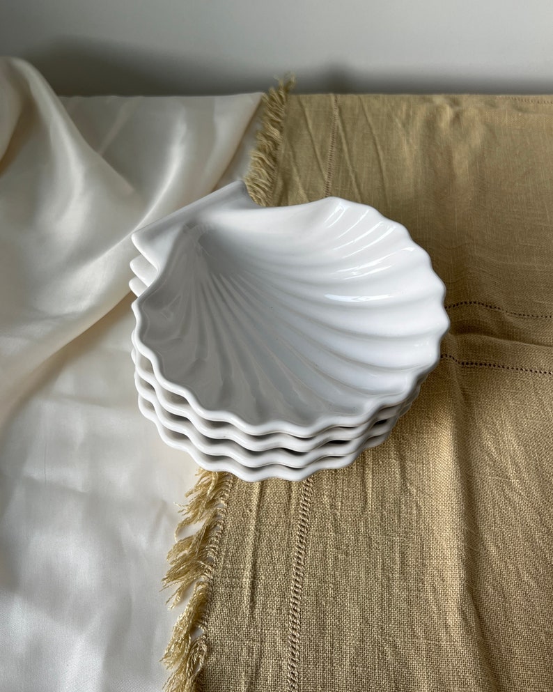 Transform your table with our Vintage Japanese Scallop Shell Ceramic Dish, a rare find from Japan. Crafted with precision and featuring a pleasant white color, this dish is ideal for baking or serving appetizers, snacks, or salads.