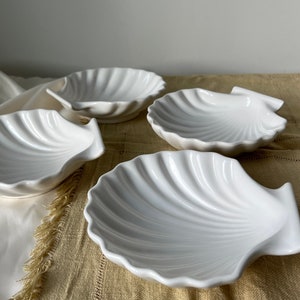 Immerse your kitchen in sophistication with our Vintage Japanese Scallop Shell Ceramic Dish. A rare gem from Japan, its high-quality craftsmanship and soft white color make it perfect for baking or serving appetizers, snacks, or salads.