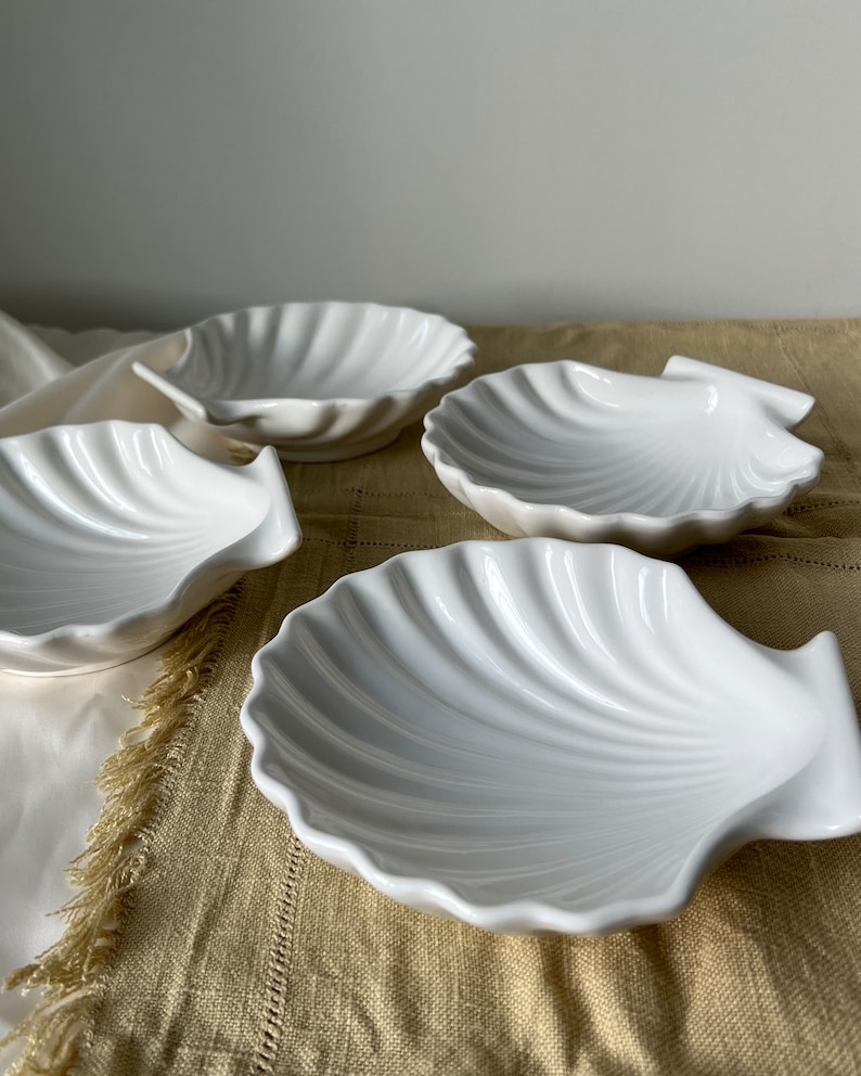 Immerse your kitchen in sophistication with our Vintage Japanese Scallop Shell Ceramic Dish. A rare gem from Japan, its high-quality craftsmanship and soft white color make it perfect for baking or serving appetizers, snacks, or salads.