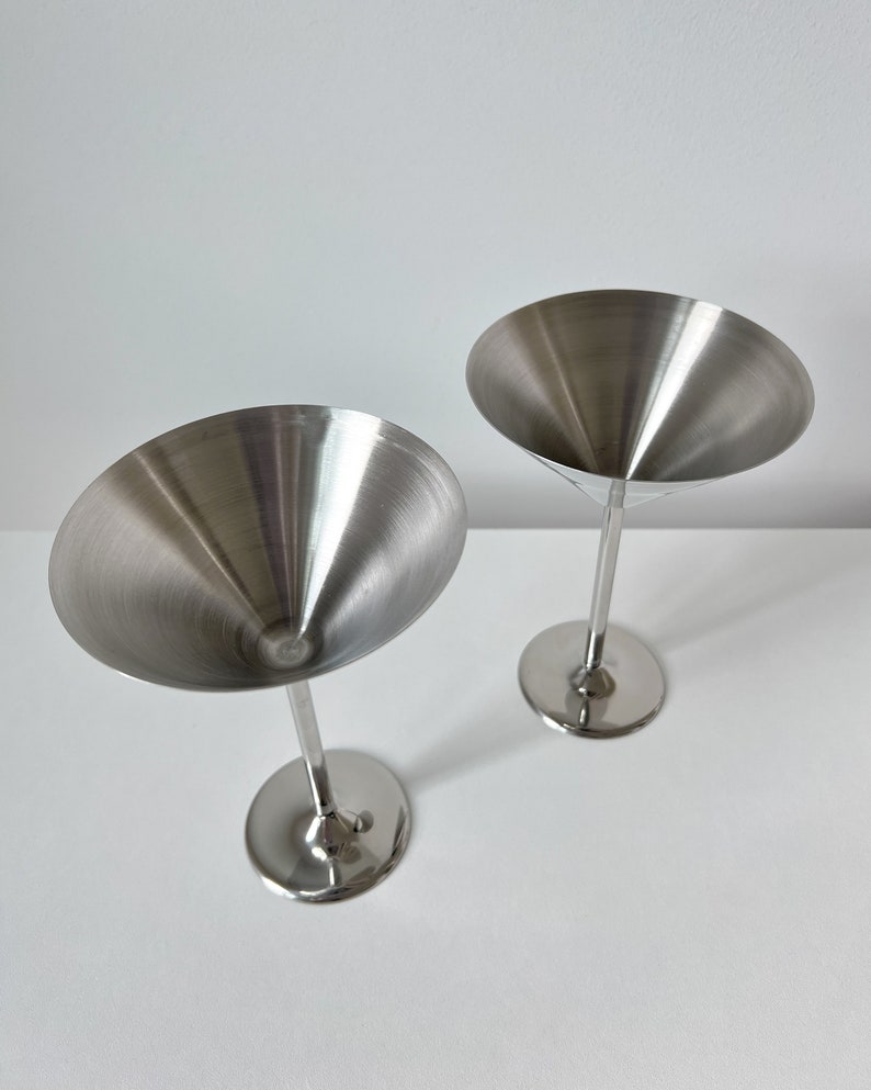 Beckmann and Rommerskirchen stainless steel cocktail dessert ice cream cups. Made in 80s Germany, their tall silver stems and sleek design add a touch of sophistication to any occasion. Serve drinks or desserts in style.