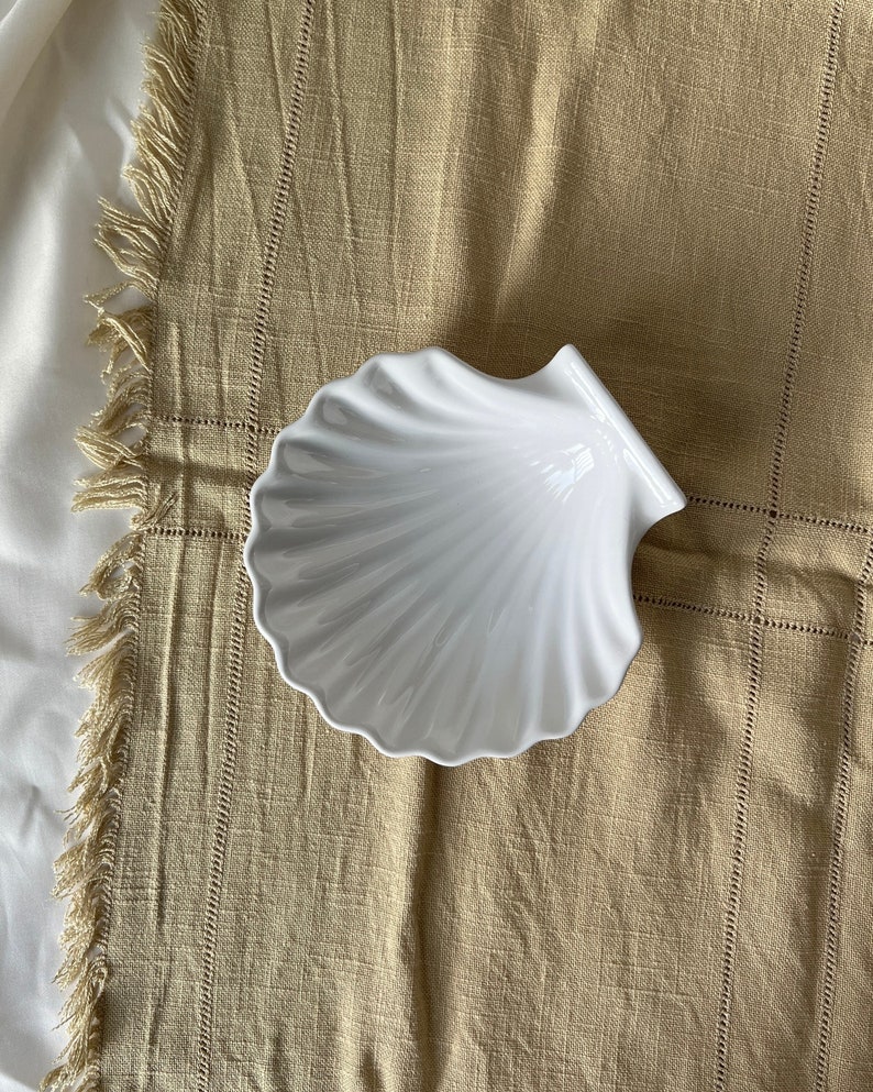 Unleash culinary creativity with our Vintage Japanese Scallop Shell Ceramic Dish, a rare find from Japan. Ideal for baking or serving, its high-quality craftsmanship and soft white color add an elegant touch.