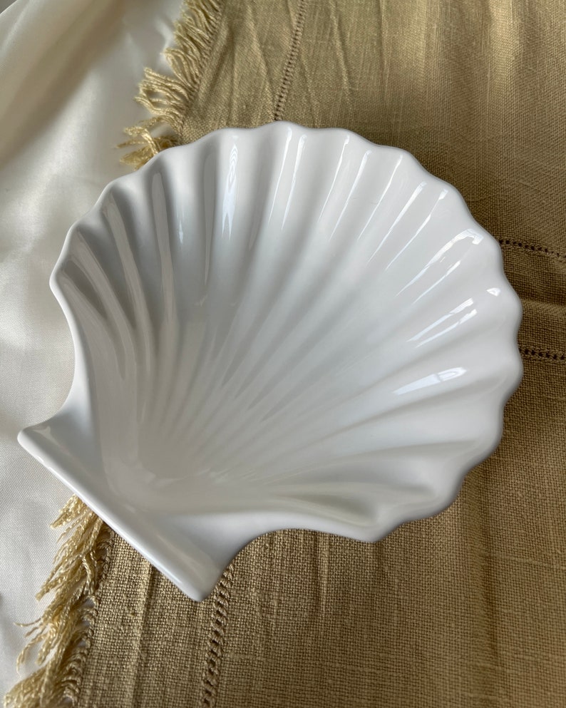 Elevate your dining experience with our Vintage Japanese Scallop Shell Ceramic Dish, a rare gem from Japan. Perfect for baking or serving, its delightful scallop shell shape and pleasant white color bring sophistication to your table.