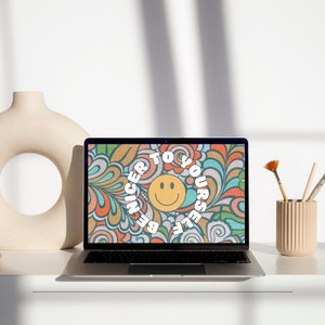 May include: A laptop computer with a colorful abstract design on the screen. The design features a smiley face with the text "Be Nicer To Yourself" around it.