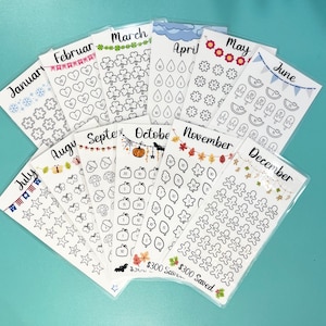 May include: Twelve sheets of monthly planner stickers with various designs for each month of the year. The stickers feature a variety of icons, including snowflakes, hearts, shamrocks, raindrops, flowers, ice cream cones, watermelons, butterflies, acorns, pumpkins, leaves, gingerbread men, and more. The stickers are printed on white paper and are packaged in clear plastic sleeves.