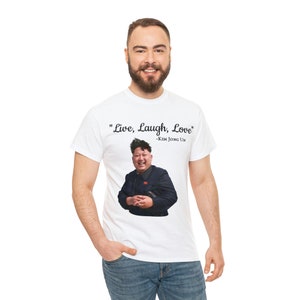 May include: White t-shirt with a black and white image of Kim Jong Un and the text "Live, Laugh, Love" - Kim Jong Un.