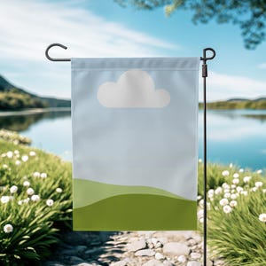 Puede incluir: Una bandera de jardín rectangular con un fondo de cielo azul claro y un gráfico de nube blanca. La parte inferior de la bandera presenta colinas verdes. La bandera está colgada de un poste de metal negro.