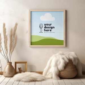 May include: A framed print with a light blue background and a white cloud. The print has a black and white illustration of a glass of champagne and the text "your design here" with the words "MOCKUP BY PRINTSTARS" below. The print is hanging on a white wall with a vase of dried pampas grass in the foreground.