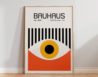 May include: A black and white poster with the text "BAUHAUS JUL-SEPT AUSSTELLUNG 1919". The poster features a stylized eye with a yellow iris and black pupil, set against a red background.
