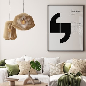 May include: A living room interior with a white couch, green throw pillows, and a throw blanket. Two woven pendant lights hang from the ceiling. A framed poster with black text that reads "Good design is as little design as possible" hangs on the wall.