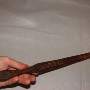 Może przedstawiać: Drewniane rzeźbienie noża z ostrym końcem i zaokrąglonym uchwytem. Nóż jest grawerowany słowami "MI HIERTZ IST FIR".