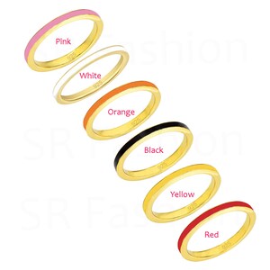 Puede incluir: Seis anillos de oro con bandas de esmalte de diferentes colores. Los anillos están dispuestos en una pila, con el anillo rosa en la parte superior y el anillo rojo en la parte inferior. Los anillos están etiquetados con sus colores: rosa, blanco, naranja, negro, amarillo y rojo. Cada anillo está marcado con "925", lo que indica que el metal es plata de ley.