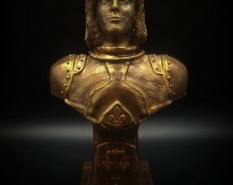 Pode incluir: Um busto de escultura de uma pessoa com armadura, de cor dourada. O busto está sobre um pedestal com um desenho de flor-de-lis.