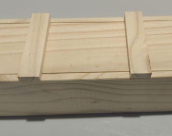 May include: A rectangular light-colored wooden box with a smooth, unfinished surface. The lid features two parallel vertical wooden slats positioned across the top, creating a simple, clean design with visible natural wood grain patterns throughout.