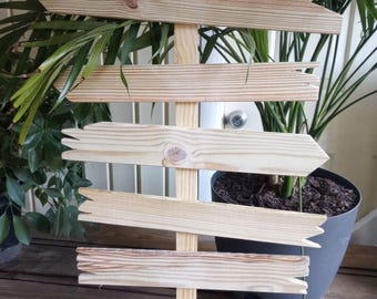May include: A wooden directional sign with six arrow-shaped planks. The sign is made of light-colored wood and is mounted on a vertical post. The arrows point in different directions, suggesting a guide or marker for a path or location.