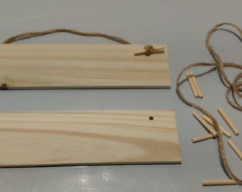 May include: Two rectangular light-colored wooden signs with natural grain patterns. One sign features a brown jute twine hanger attached through two pre-drilled holes. The set includes a length of loose jute twine and several small wooden dowels.