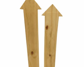 May include: Two wooden arrow-shaped signs with natural wood grain. The arrows point upwards, and each has a triangular head. The wood has visible knots and a light brown color, suggesting a rustic or handmade aesthetic.