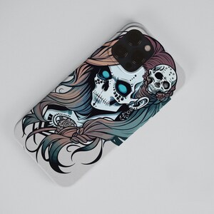 May include: A white phone case with a colorful illustration of a skull with blue eyes and long hair. The skull is wearing a flower crown and has a smaller skull on the side of its head.