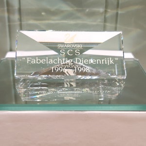 Può includere: Un premio in vetro trasparente con la scritta "Swarovski SCS "Fabelachtig Dierenrijk" 1996 - 1998" su di esso. Il premio è posto su una scatola bianca con la scritta "VDF Antiques & Collectibles" su di essa.