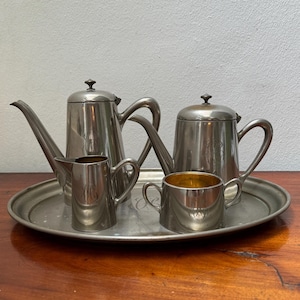 May include: A silver tea set on a silver tray. The set includes a teapot, a creamer, and two sugar bowls.