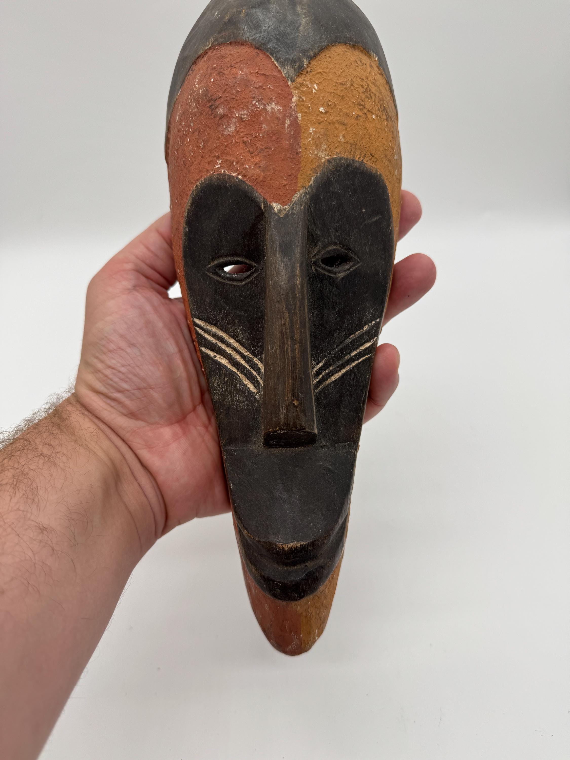 赤、黄、黒の顔料を使用した小さなアフリカの部族のマスク – 手彫りの