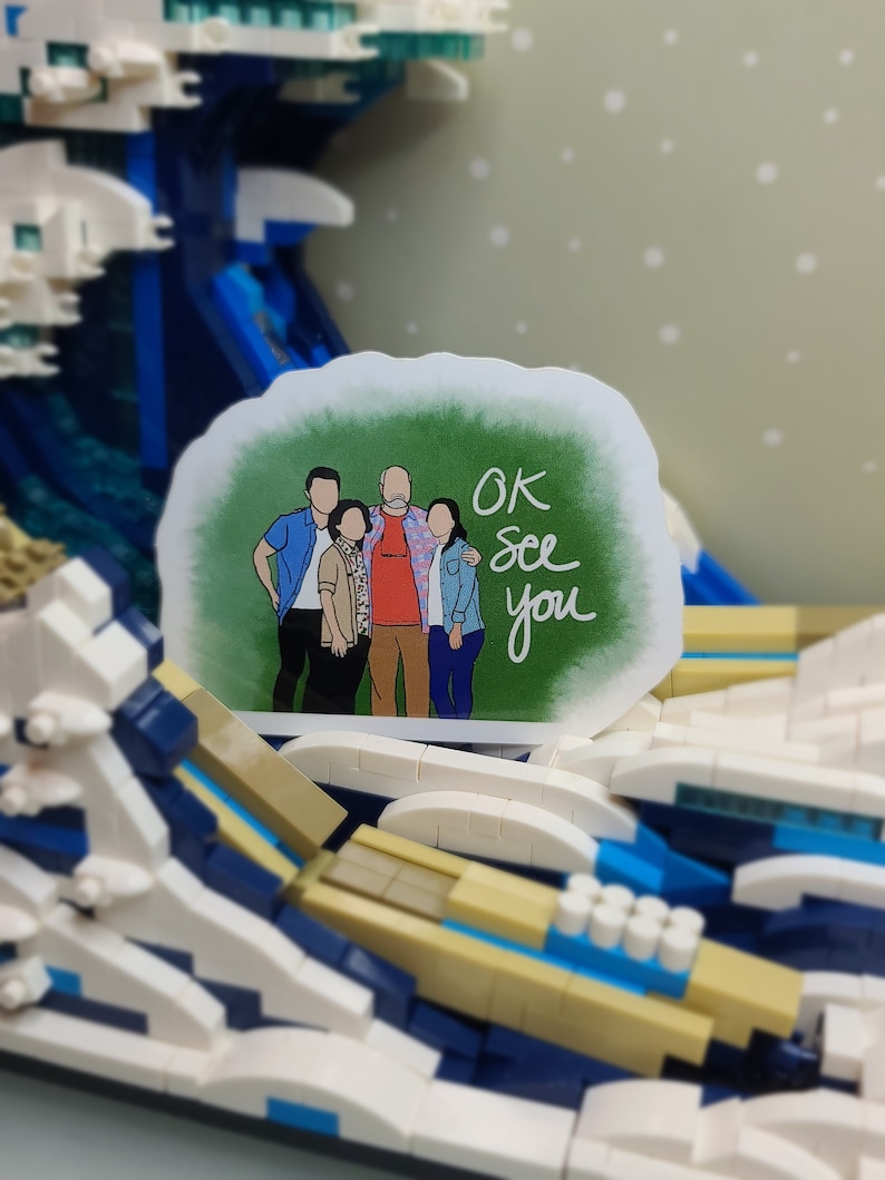 May include: A sticker featuring a family portrait with the text "OK See you" in a handwritten style. The sticker is set against a backdrop of a Lego wave, with shades of blue, white, and tan.