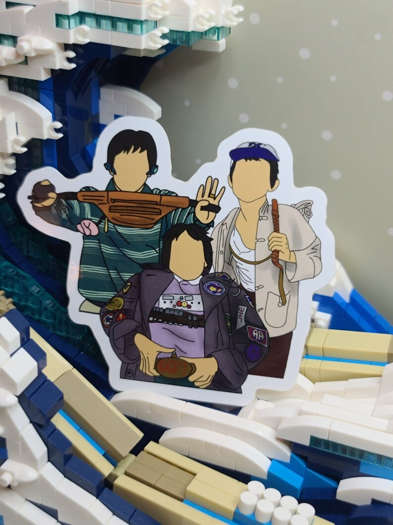 May include: A sticker featuring a cartoon illustration of three people. One person is wearing a striped shirt and holding a brown fanny pack. Another is wearing a white jacket and holding a stick. The third person is wearing a purple jacket.