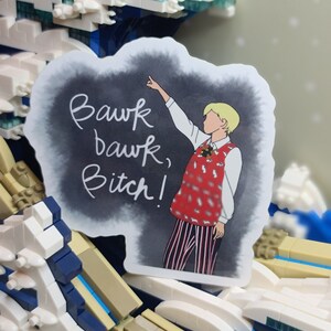 May include: A sticker featuring a cartoon illustration of a person pointing upwards, with the text "Bawk bawk, Bitch!" on a dark background. The person is wearing a red vest with a white shirt and striped pants.