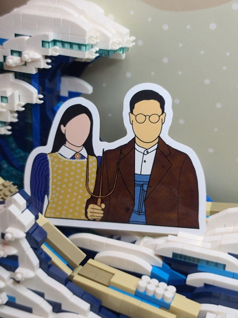 May include: A sticker featuring a parody of the American Gothic painting, with the figures' faces blank. The figures are holding a pitchfork. The sticker is set against a backdrop of a Lego wave.