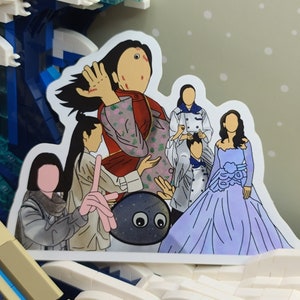 May include: A sticker featuring a group of cartoon figures, including a woman in a red and floral patterned jacket, a woman in a blue gown, and a gray rock with eyes. The sticker is set against a backdrop of a Lego wave.