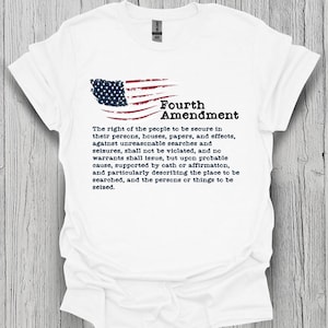 May include: A white short-sleeved t-shirt featuring a graphic of a stylized American flag and the text Fourth Amendment followed by the full text of the Fourth Amendment to the United States Constitution printed in black ink on the front.