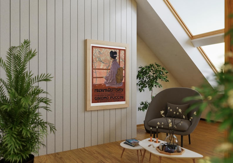 May include: A framed poster with a red background and a woman in a purple dress standing in front of a Japanese garden. The poster reads "Madame Butterfly" and "Giacomo Puccini".