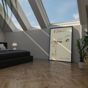 May include: A bedroom scene with a black bed, a Vogue poster, and potted plants. The Vogue poster features an illustration of an eye and hand applying makeup. The room has a wooden floor and a skylight.