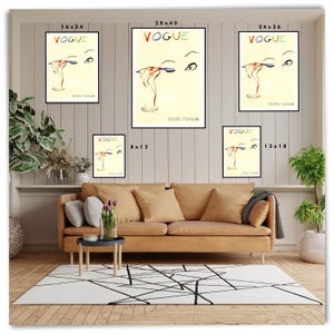 May include: A collection of framed Vogue art prints in various sizes. Each print features a stylized illustration of an eye with makeup application, with the word "VOGUE" in colorful letters at the top. The prints are displayed above a tan sofa.