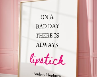 May include: A white framed poster with a quote about lipstick. The quote reads "On a bad day there is always lipstick." The quote is attributed to Audrey Hepburn.