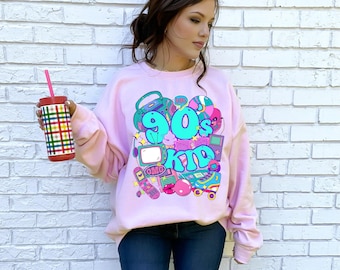 May include: Pink sweatshirt with a graphic print of a 90s kid theme. The graphic includes a boombox, a television, a cell phone, a roller skate, and the text "90's Kid".