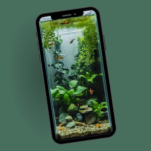 May include: A smartphone screen displays a miniature aquarium scene. The tank features lush green plants, rocks, and small orange fish. The aquarium is lit with a bright light, creating a vibrant underwater environment. The phone has a black frame.