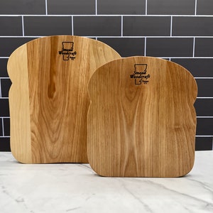 May include: Two wooden cutting boards shaped like slices of bread. Both boards have the text "Smead Woodcraft" and a small image of the state of Vermont.