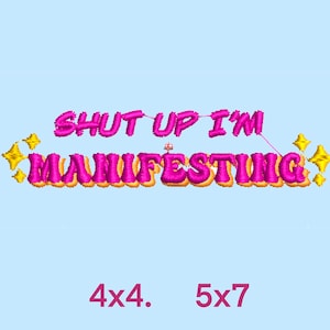 May include: Pink and yellow embroidered design with the text "Shut Up I'm Manifesting" and two gold stars on a light blue background.